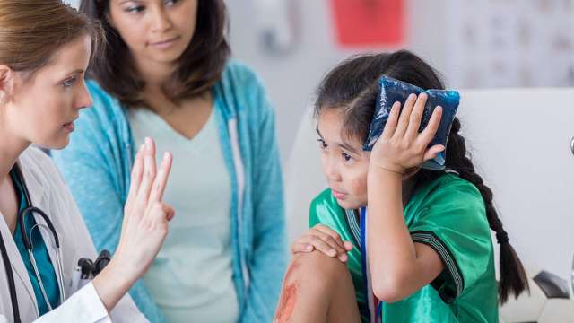 Little girl and mother at a doctors appointment being helped by a medical professional 